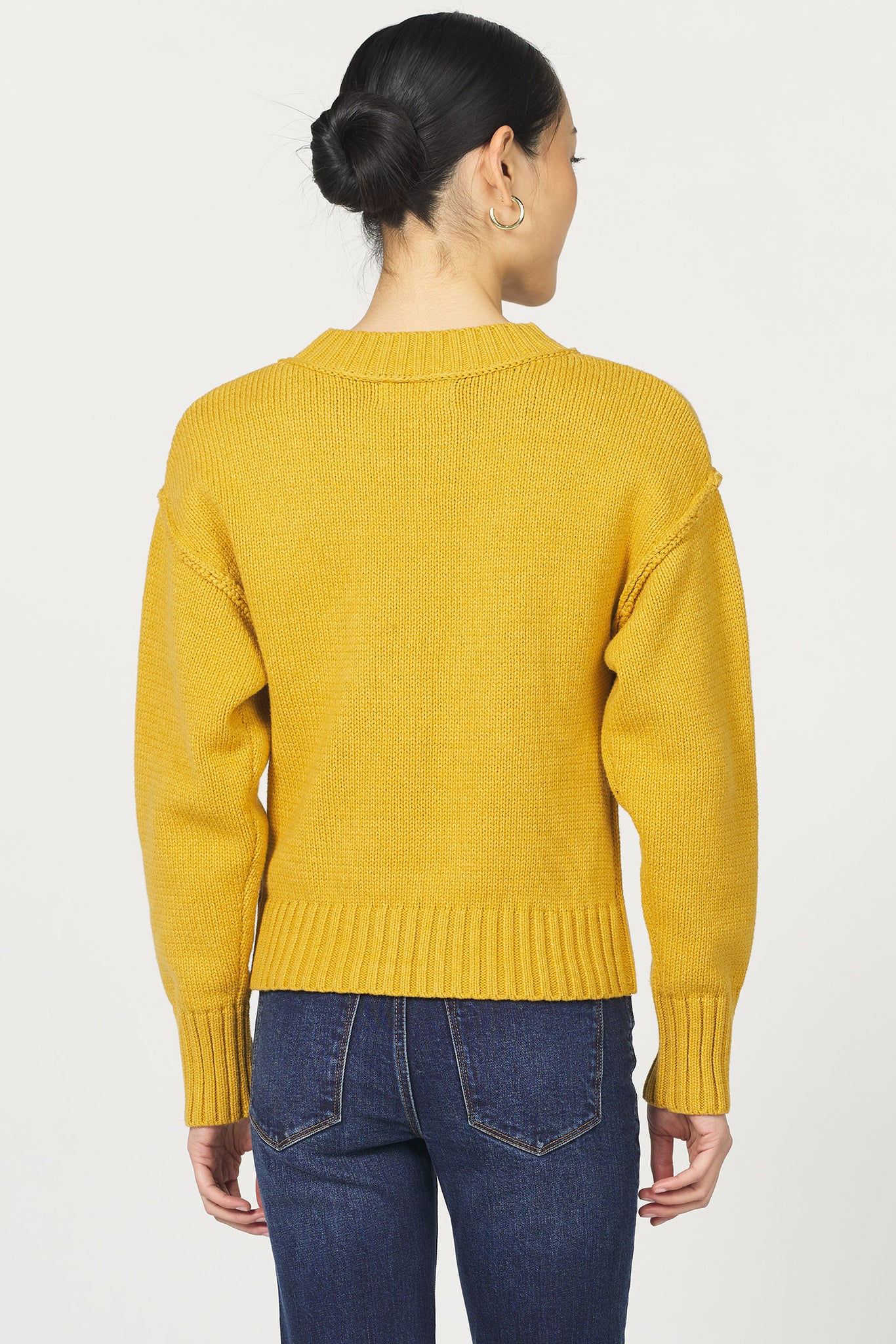 Person wearing a yellow sweater and blue jeans on a white background