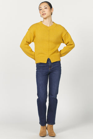 Person wearing a yellow sweater and blue jeans on a white background