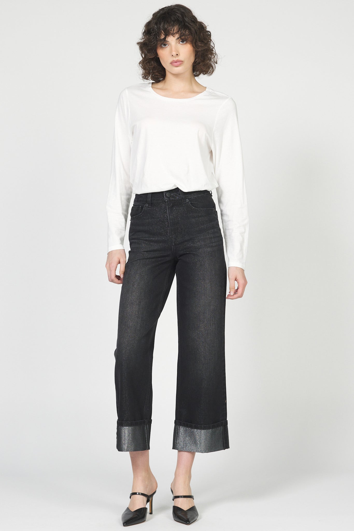 Woman wearing a white blouse and black wide-leg jeans on a white background