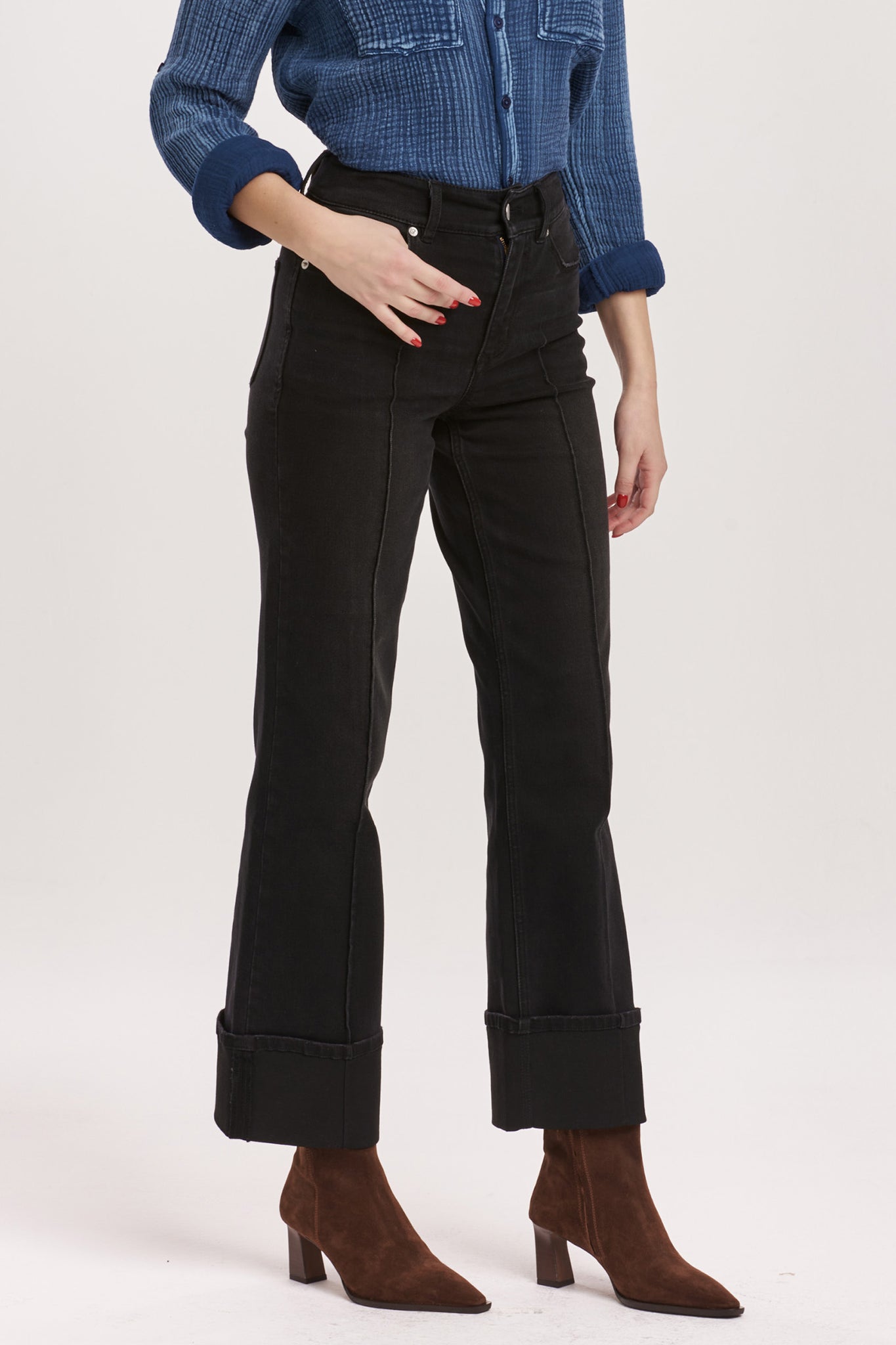 Person wearing black jeans and a blue checkered shirt on a white background