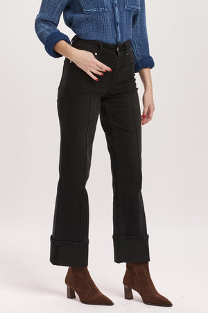 Person wearing black jeans and a blue checkered shirt on a white background