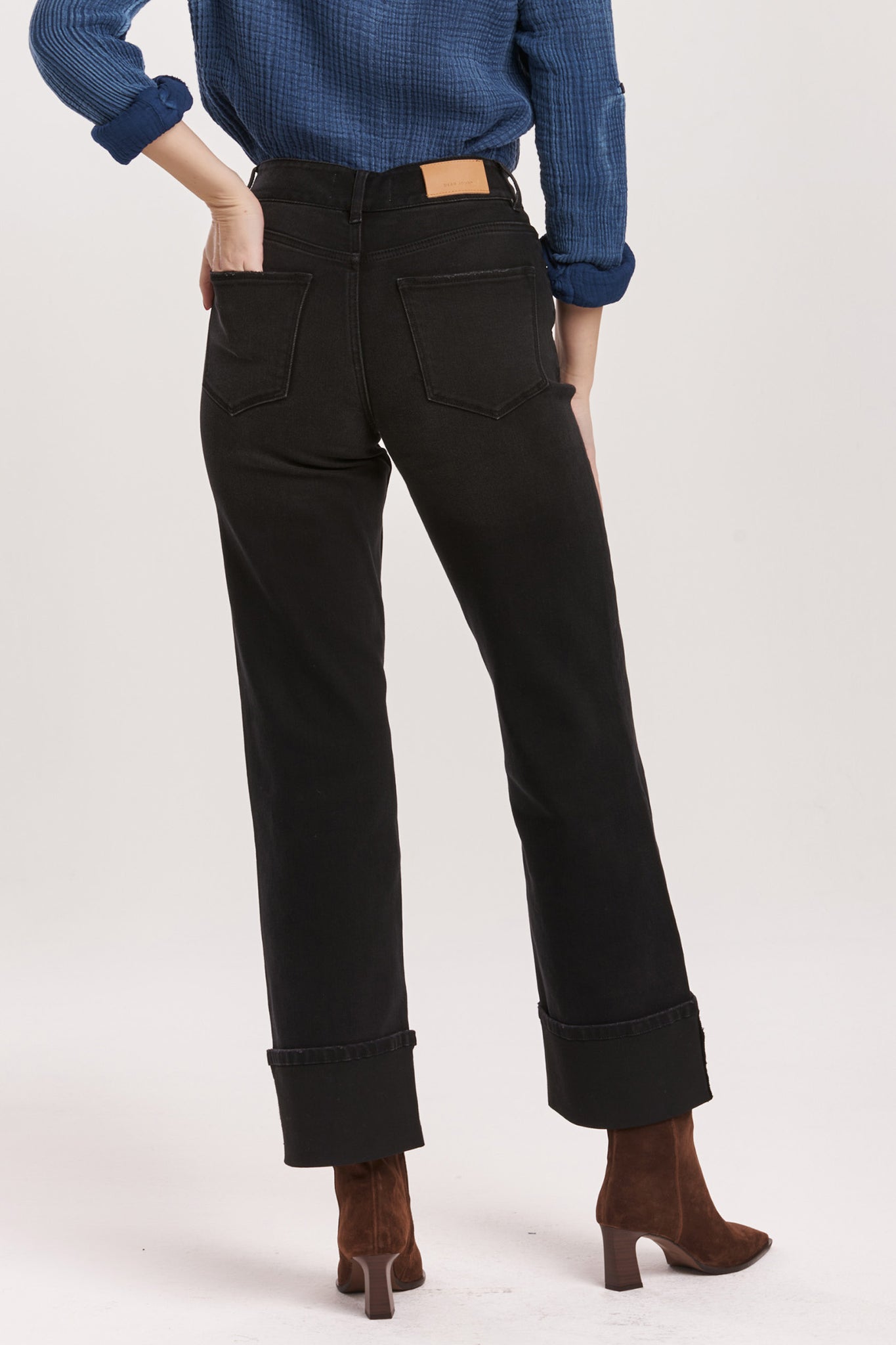 Person wearing black pants and a blue shirt on a white background