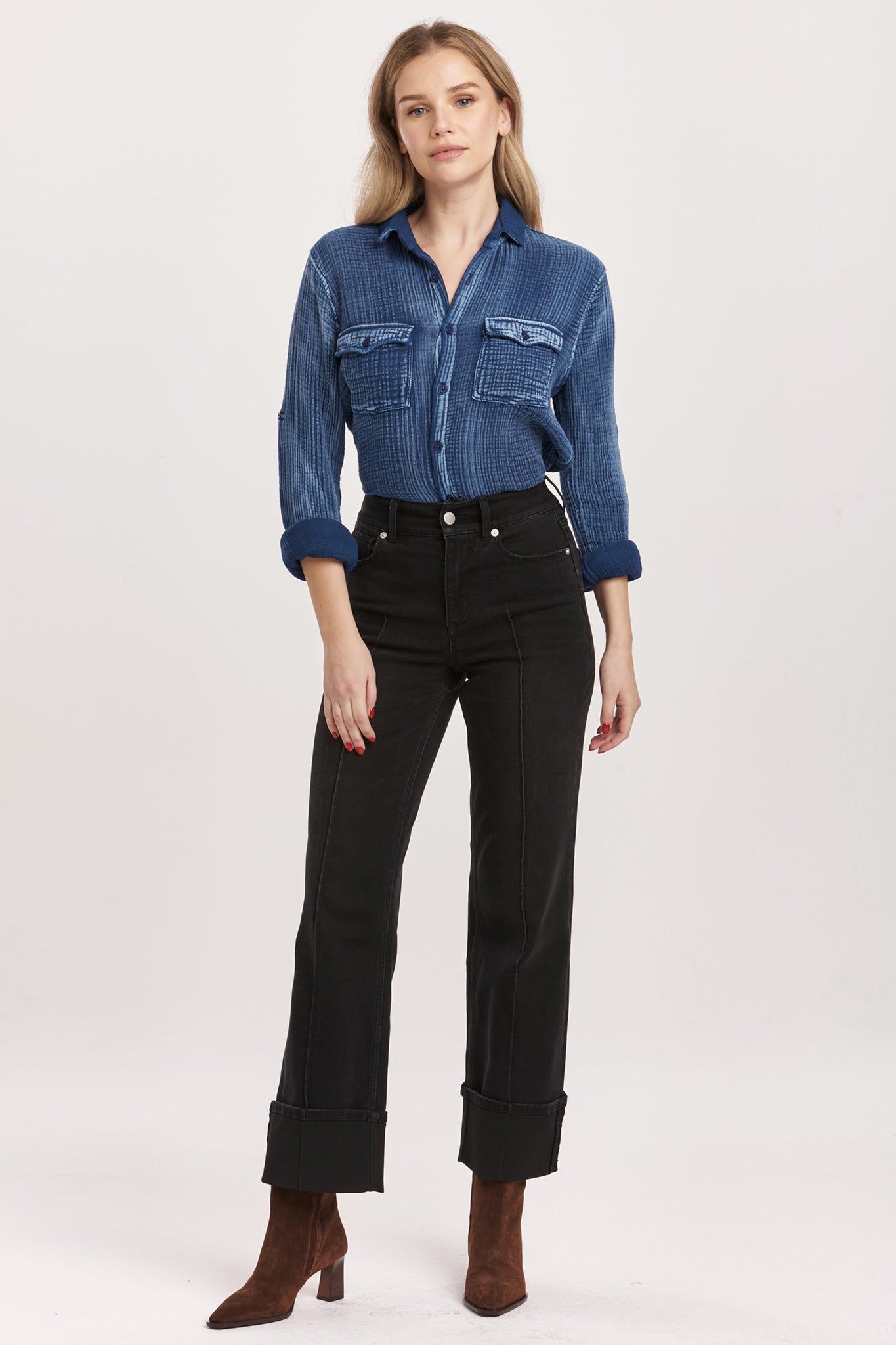 Woman wearing a blue denim shirt and black jeans on a white background