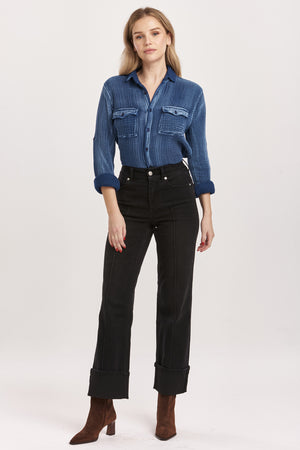 Woman wearing a blue denim shirt and black jeans on a white background