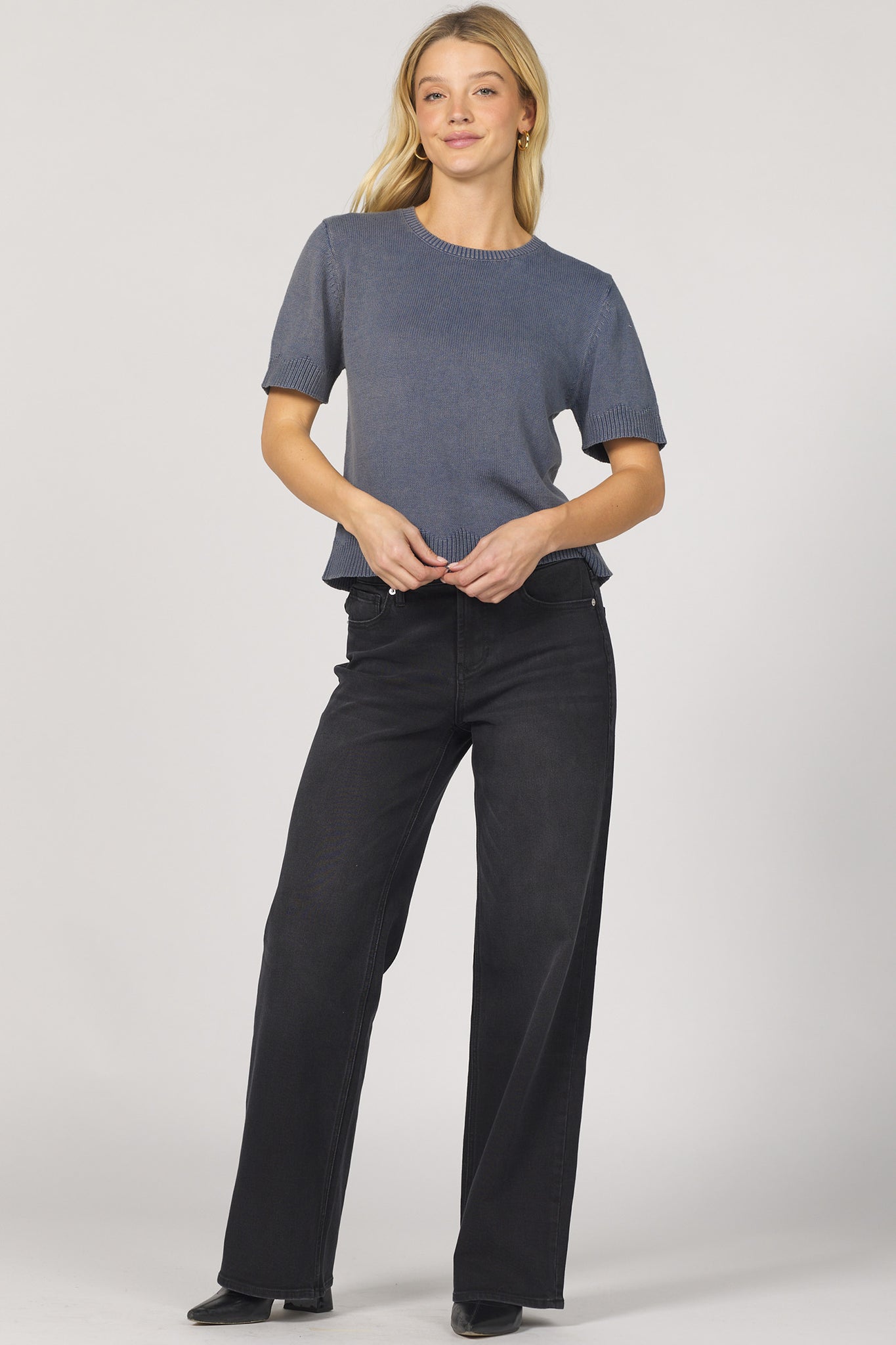 Woman wearing a gray shirt and black pants on a white background