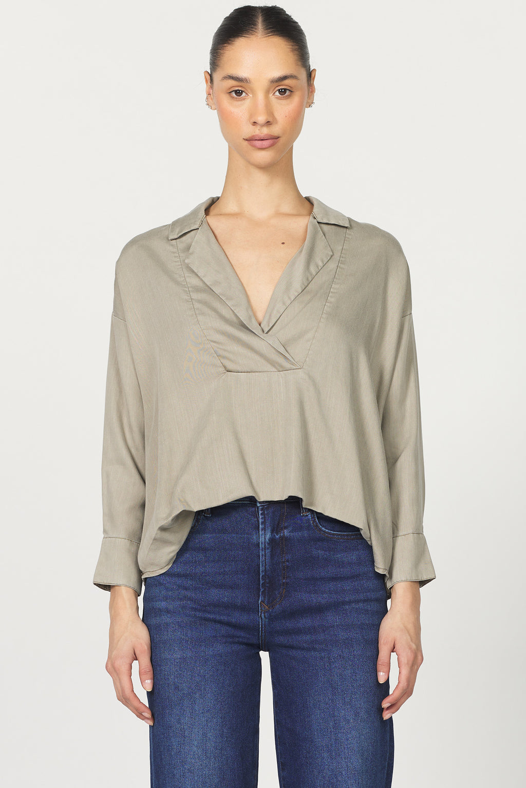 Woman wearing a beige blouse and blue jeans on a white background