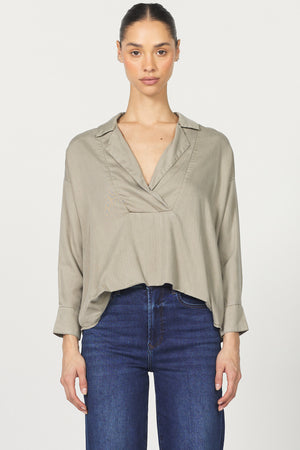 Woman wearing a beige blouse and blue jeans on a white background