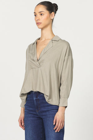 Woman wearing a beige blouse and blue jeans on a white background