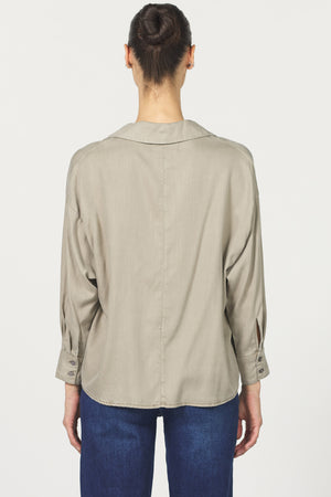 Person wearing a beige shirt and blue jeans on a white background