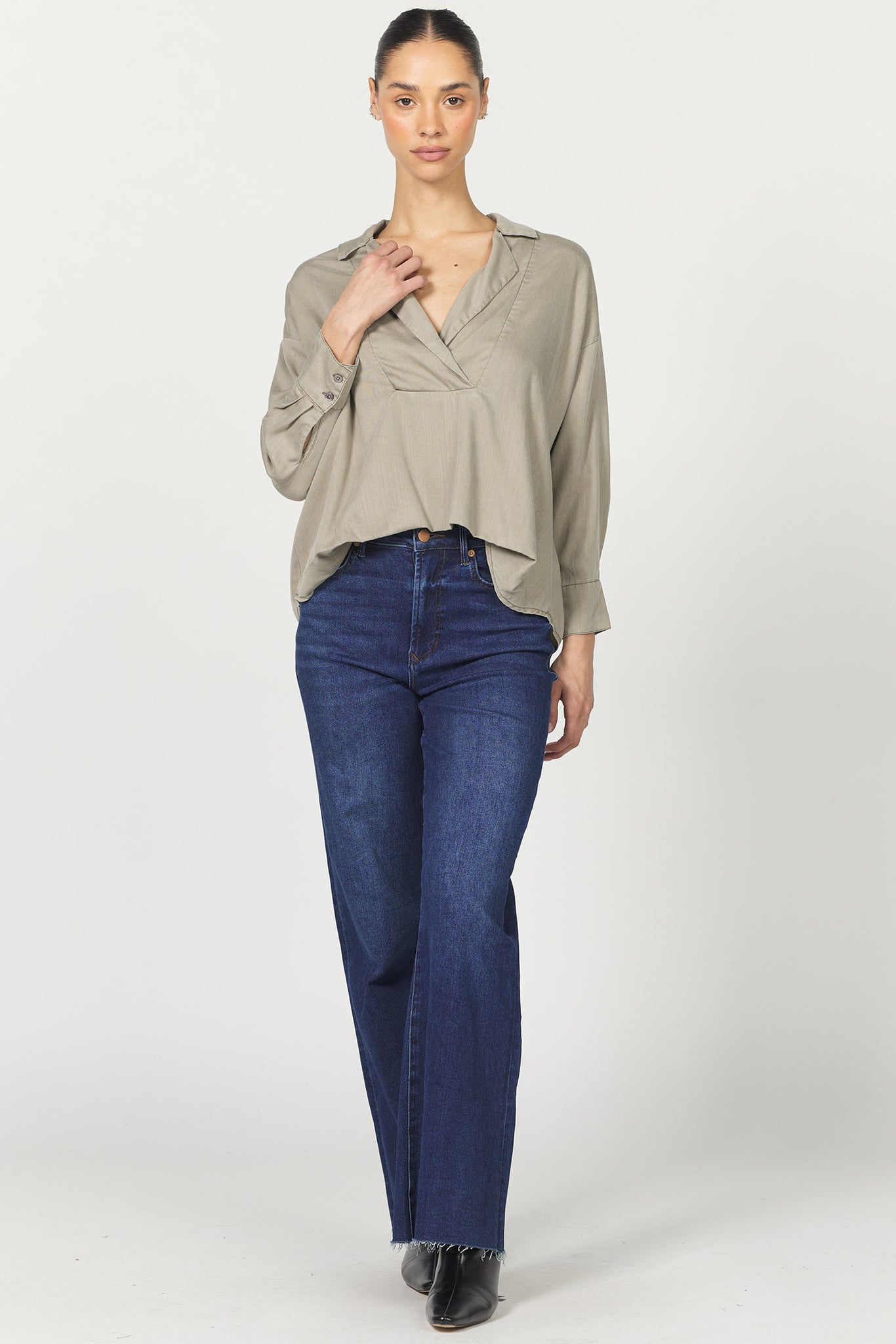 Woman wearing a beige blouse and blue jeans on a white background