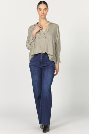 Woman wearing a beige blouse and blue jeans on a white background