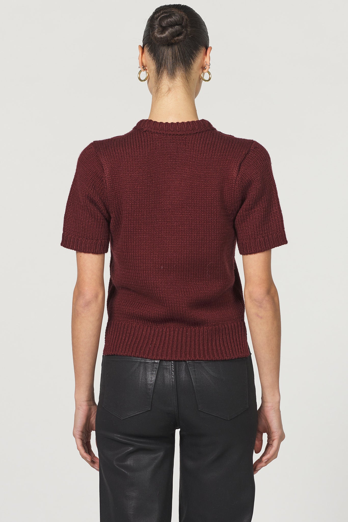 Person wearing a maroon sweater and black pants on a white background