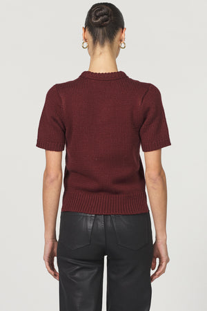 Person wearing a maroon sweater and black pants on a white background