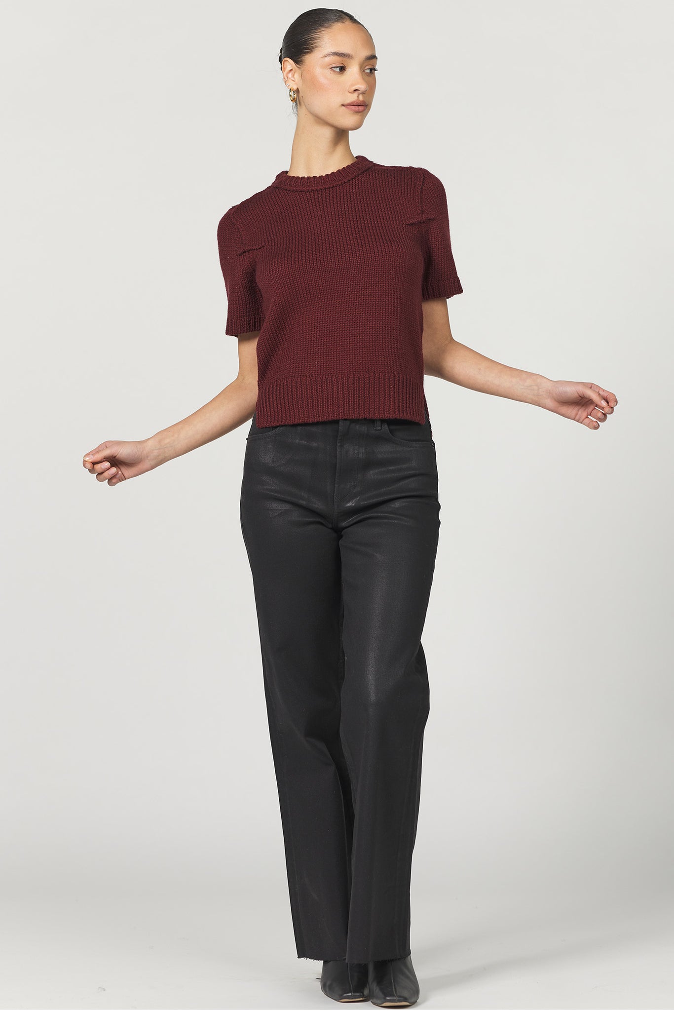 Woman wearing a burgundy sweater and black pants on a white background