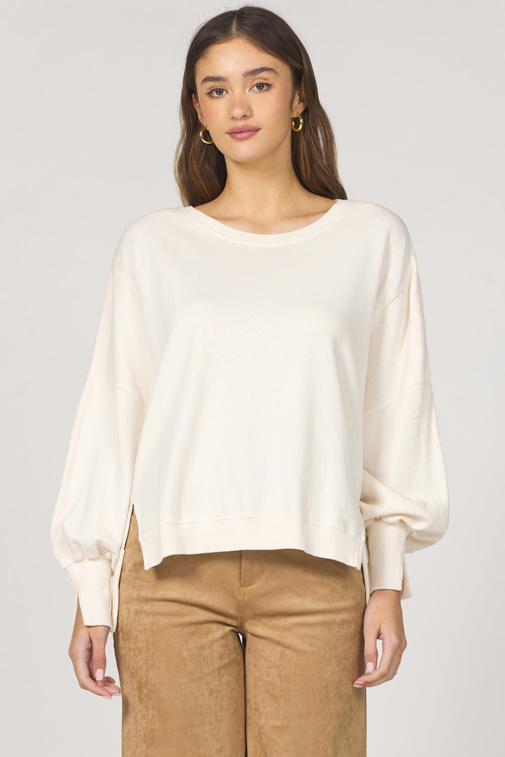 Woman wearing a white blouse and brown pants on a plain background