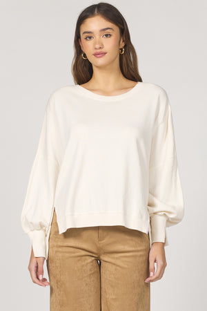 Woman wearing a white blouse and brown pants on a plain background