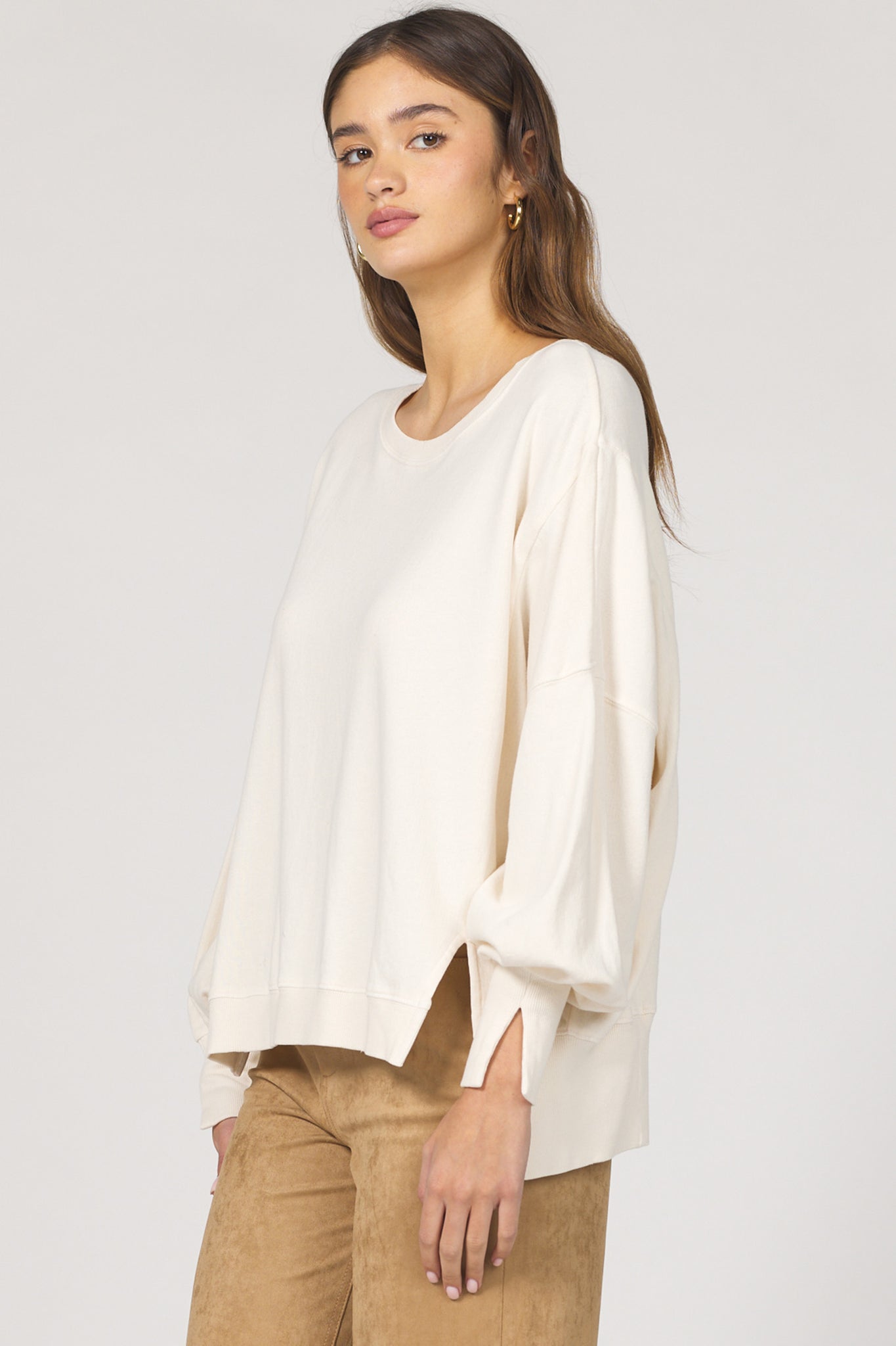 Woman wearing a white blouse and brown pants on a plain background