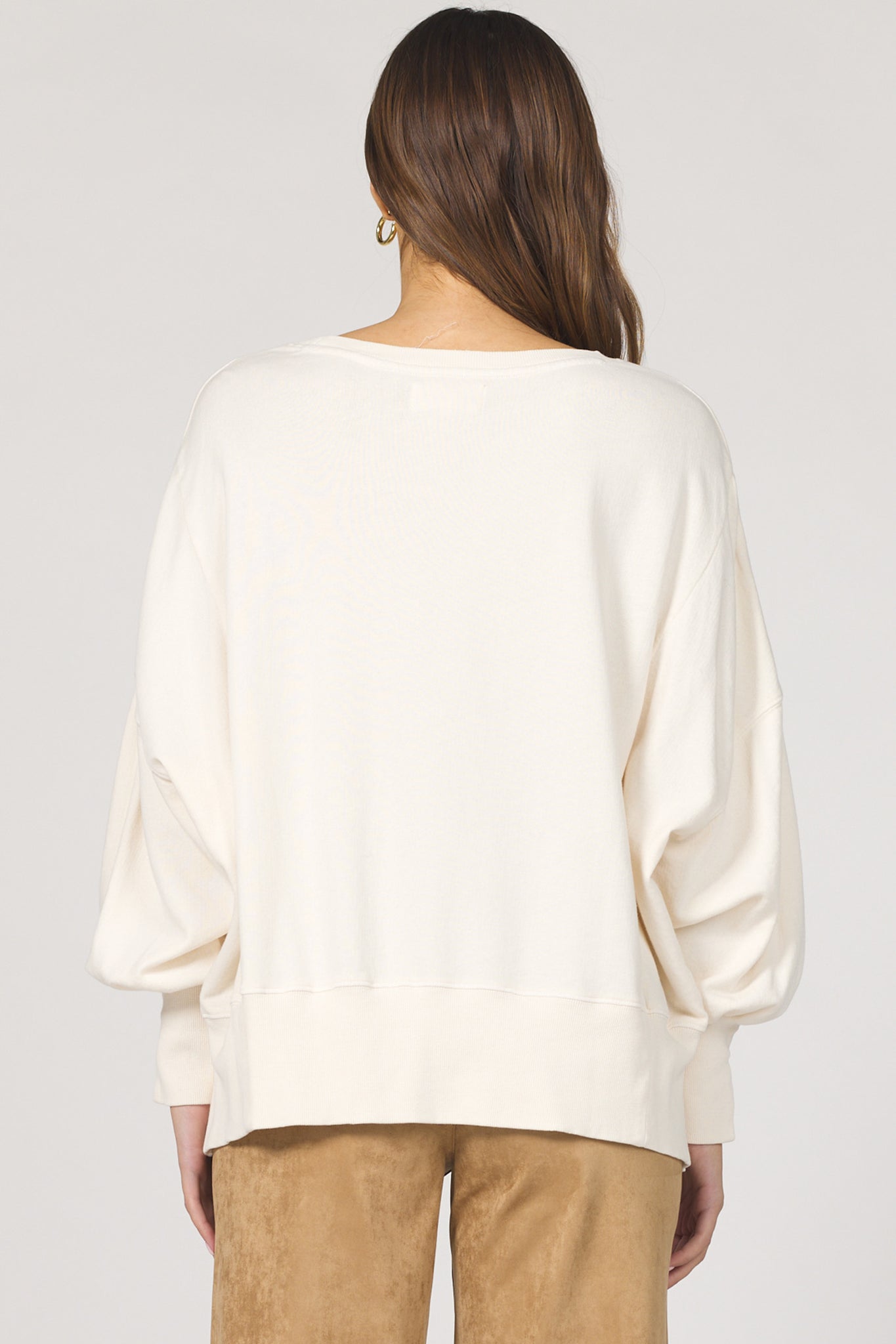 Person wearing a white blouse with long sleeves on a plain background