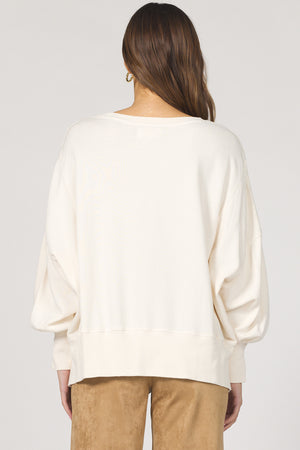 Person wearing a white blouse with long sleeves on a plain background