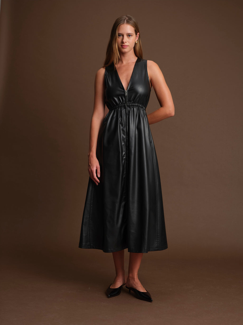 Woman wearing a black leather dress against a brown background