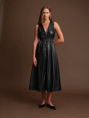 Woman wearing a black leather dress against a brown background