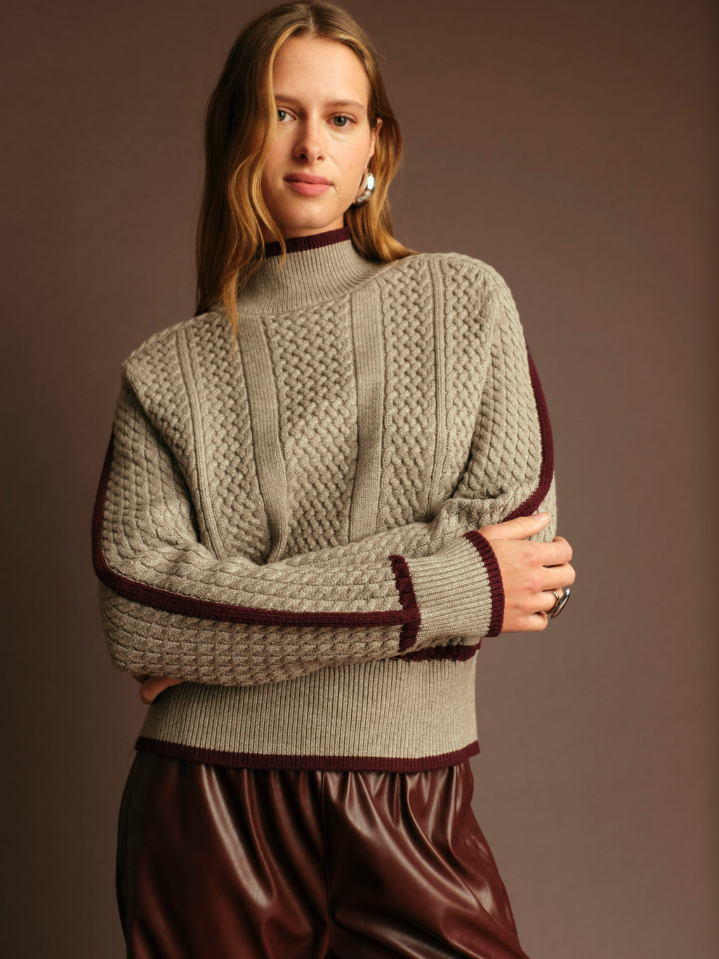 Woman wearing a knitted sweater with a plain background