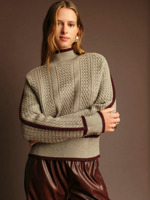 Woman wearing a knitted sweater with a plain background