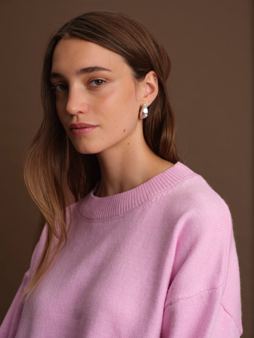Woman wearing a light purple sweater against a brown background