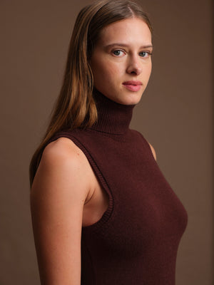 Woman wearing a brown sleeveless turtleneck against a brown background