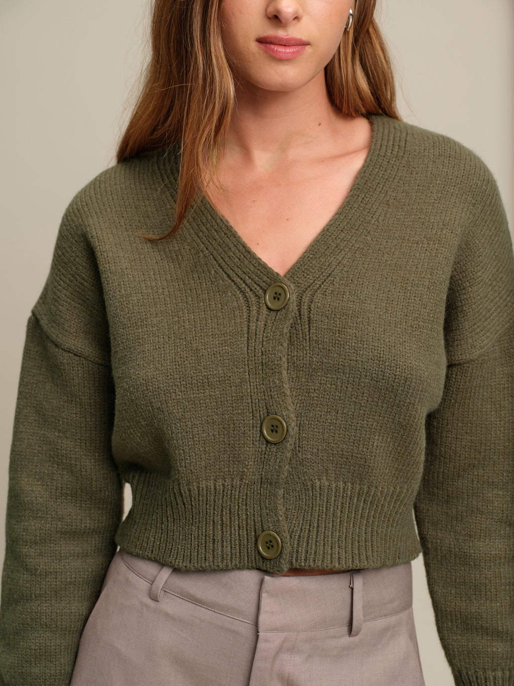 Person wearing a green cardigan against a neutral background