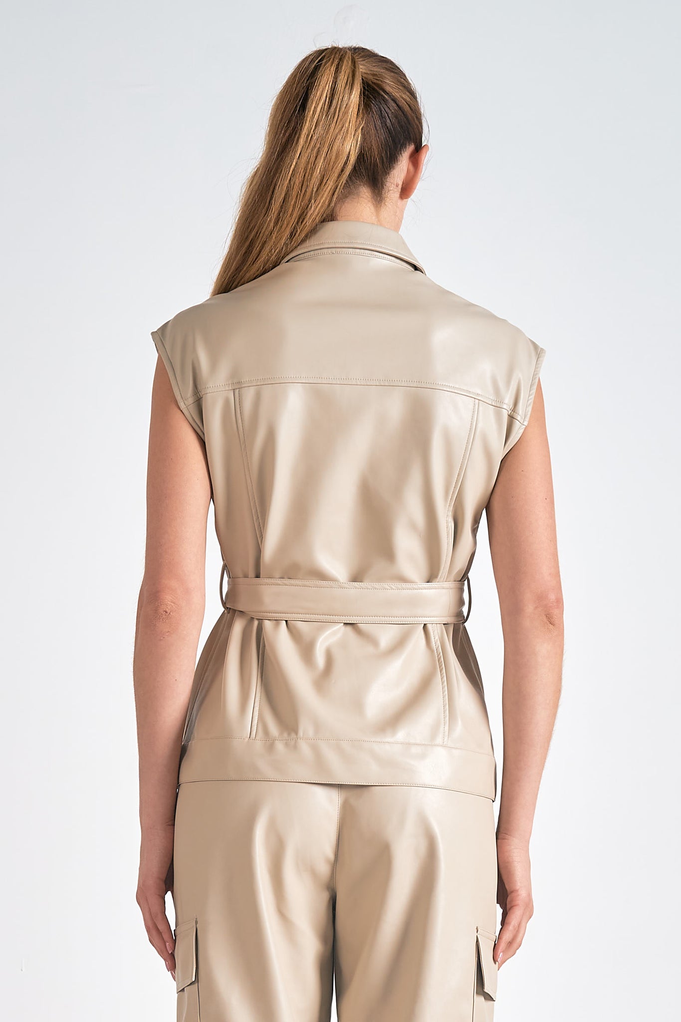 Introducing the Elan | Mikey vest - a faux leather vest with a twist! The belted design adds a touch of edginess to any outfit, while the faux leather material adds a touch of luxury. Walk the streets in style and turn heads with this unique and versatile piece.