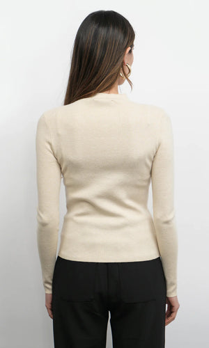 Woman wearing a beige long-sleeve top against a white background