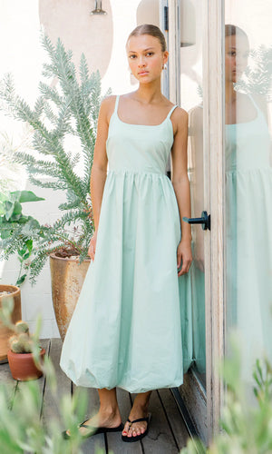 This midi dress is defined by it's bold and playful bubble skirt. The structure showcases hidden pockets, a smocked back, and a square neckline.