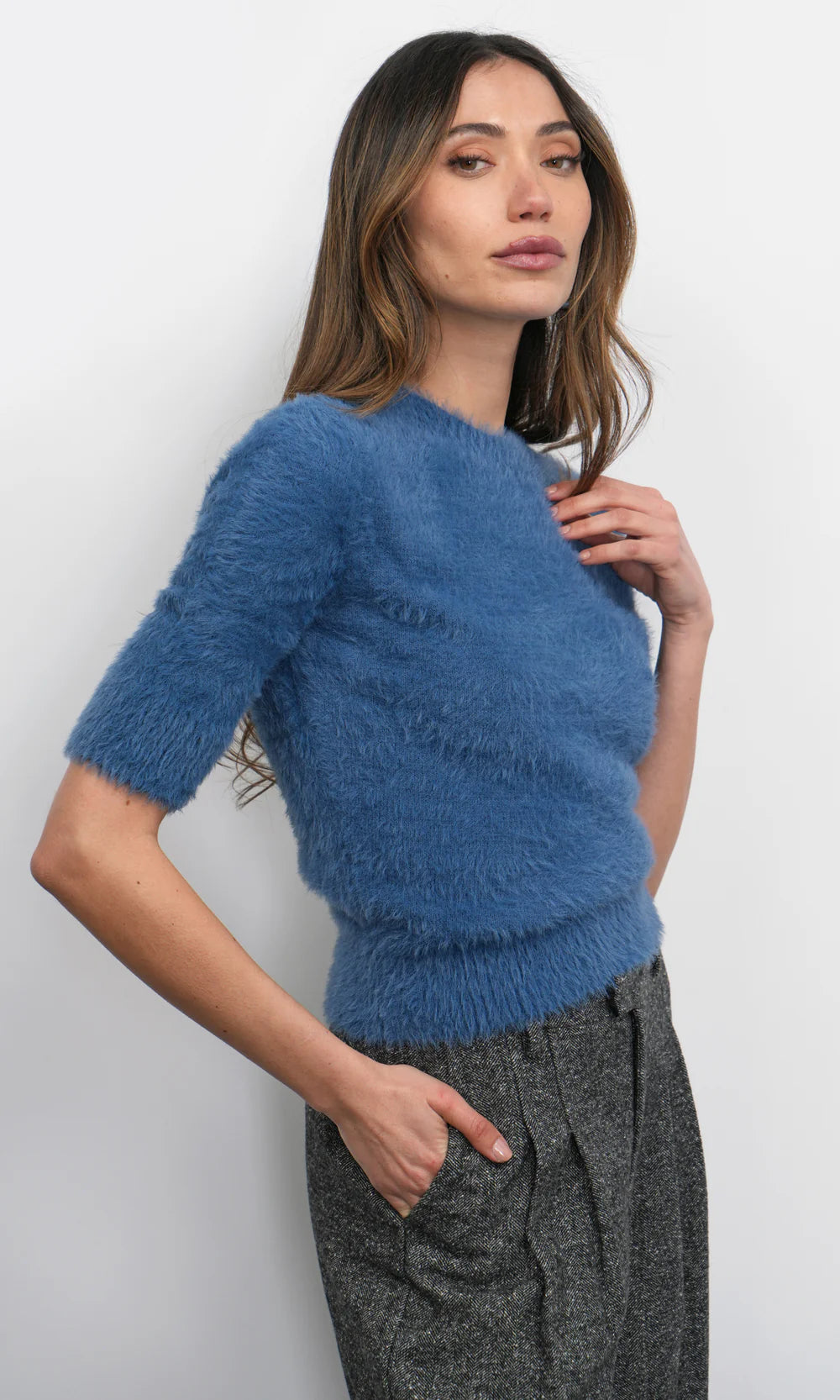 Woman wearing a blue fuzzy sweater against a white background