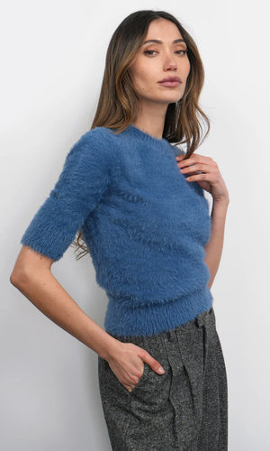 Woman wearing a blue fuzzy sweater against a white background
