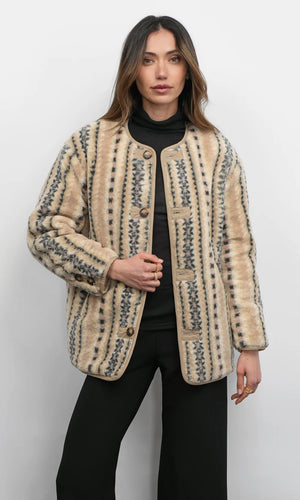 Woman wearing a patterned beige jacket against a white background