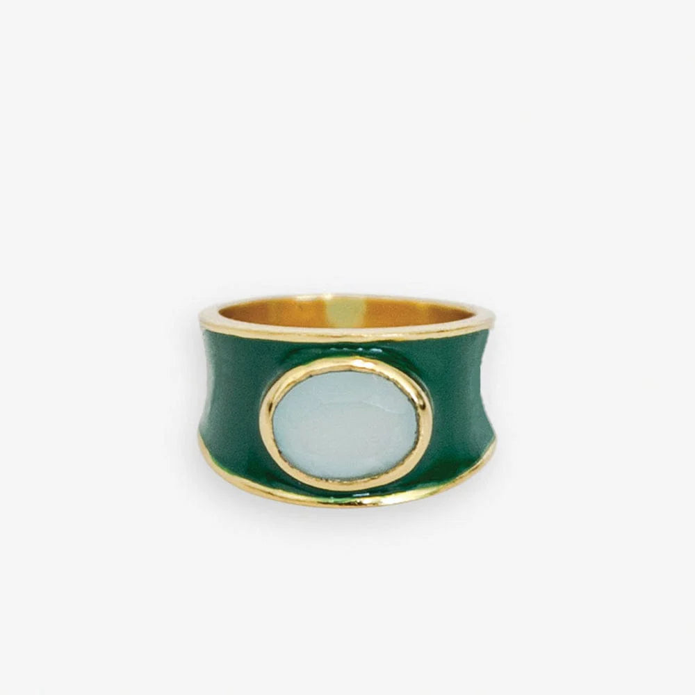 Make a bold statement with the Hazel Oval Stone with Enamel Band Ring. This cocktail ring features an oval-shaped semi-precious stone, such as Black Onyx, Red Jade, Green Onyx, Rainbow Moonstone, or other colors, surrounded by an enamel band. It adds a touch of sophistication and elegance to any outfit.