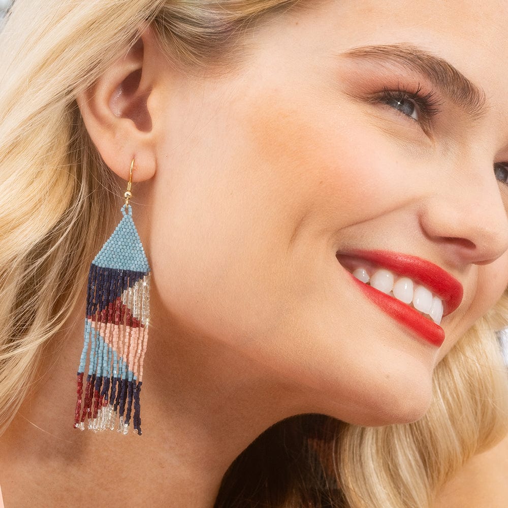 Close-up of a woman wearing colorful beaded earrings with a blurred background