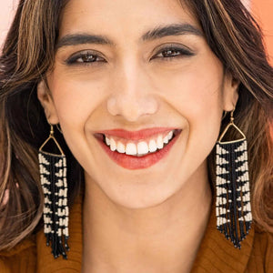 Close-up of a woman wearing black and white beaded earrings with a blurred background