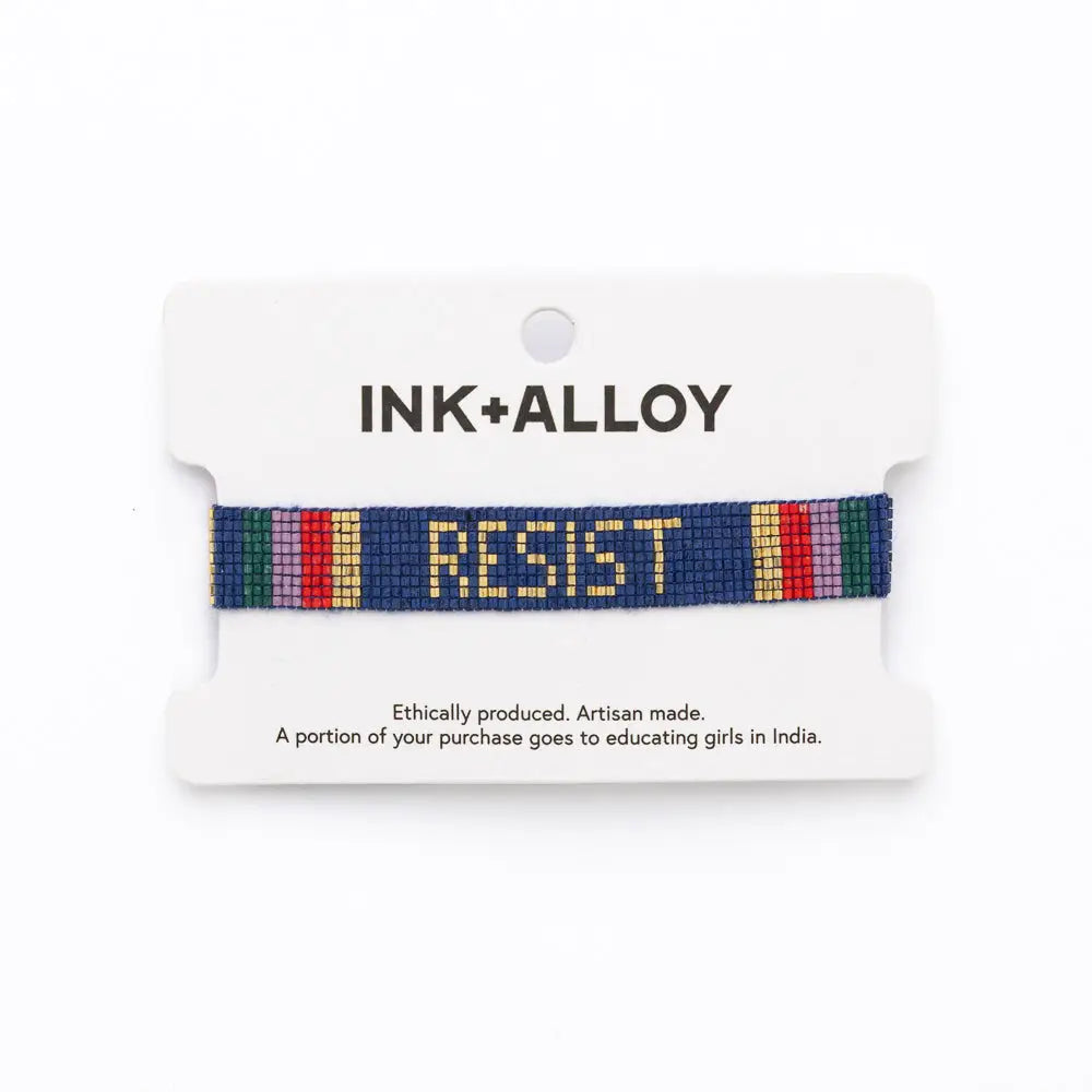 Bracelet with 'RESIST' on a white card with 'INK+ALLOY' branding