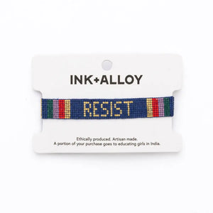 Bracelet with 'RESIST' on a white card with 'INK+ALLOY' branding