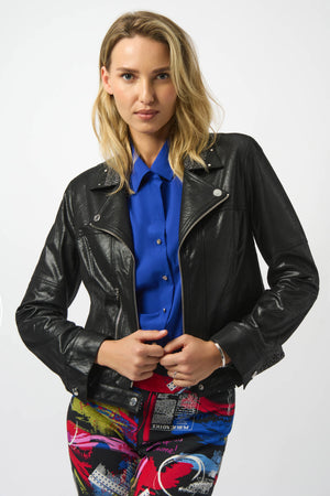 Woman wearing a black leather jacket over a blue shirt with colorful pants on a white background