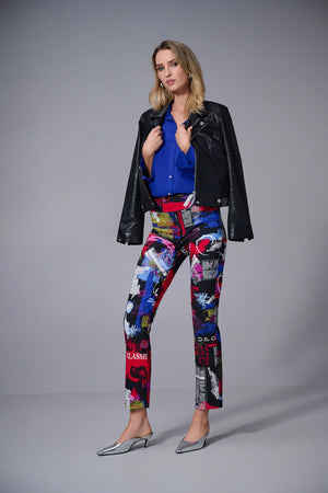 Woman wearing a black leather jacket, blue shirt, and colorful patterned pants on a gray background