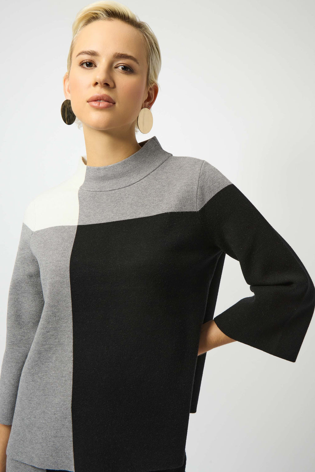 Woman wearing a black and gray color-blocked sweater on a white background