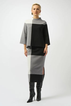 Person wearing a black, gray, and white color-blocked outfit with a cape on a white background