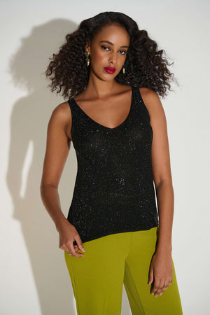 Woman wearing a black sleeveless top and green pants against a white background