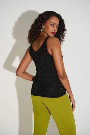Woman wearing a black top and green pants against a white background