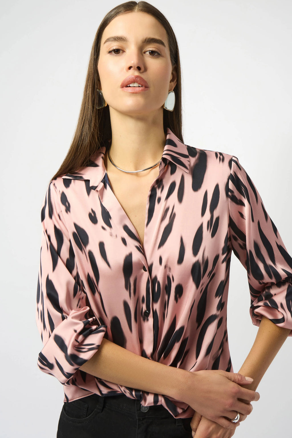 Woman wearing a pink blouse with black animal print pattern on a white background