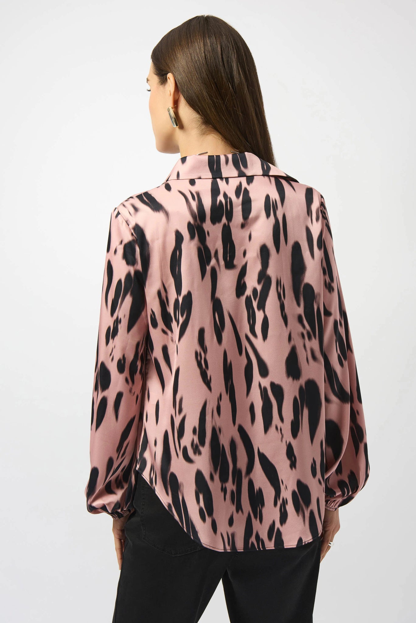 Woman wearing a pink blouse with black leopard print pattern on a white background