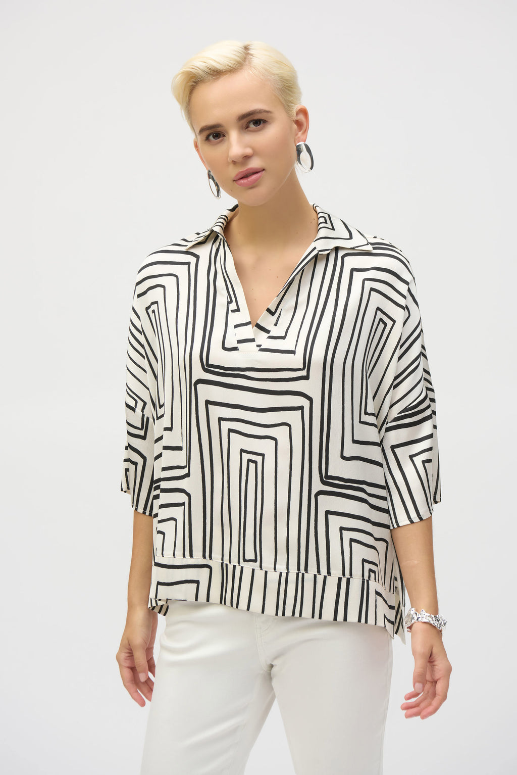 A striking illustration of artistry and poise, this satin top adds flair to every ensemble. The piece boasts an alluring geometric print on a boxy silhouette, the epitome of bold contemporary style. The V-shaped neckline with shirt collar as well as the three-quarter dolman sleeves with cuffs lend a polished feel to this chic garment. A band at the hem and side slits adorn the top, the perfect touch to elevate this incredible piece.